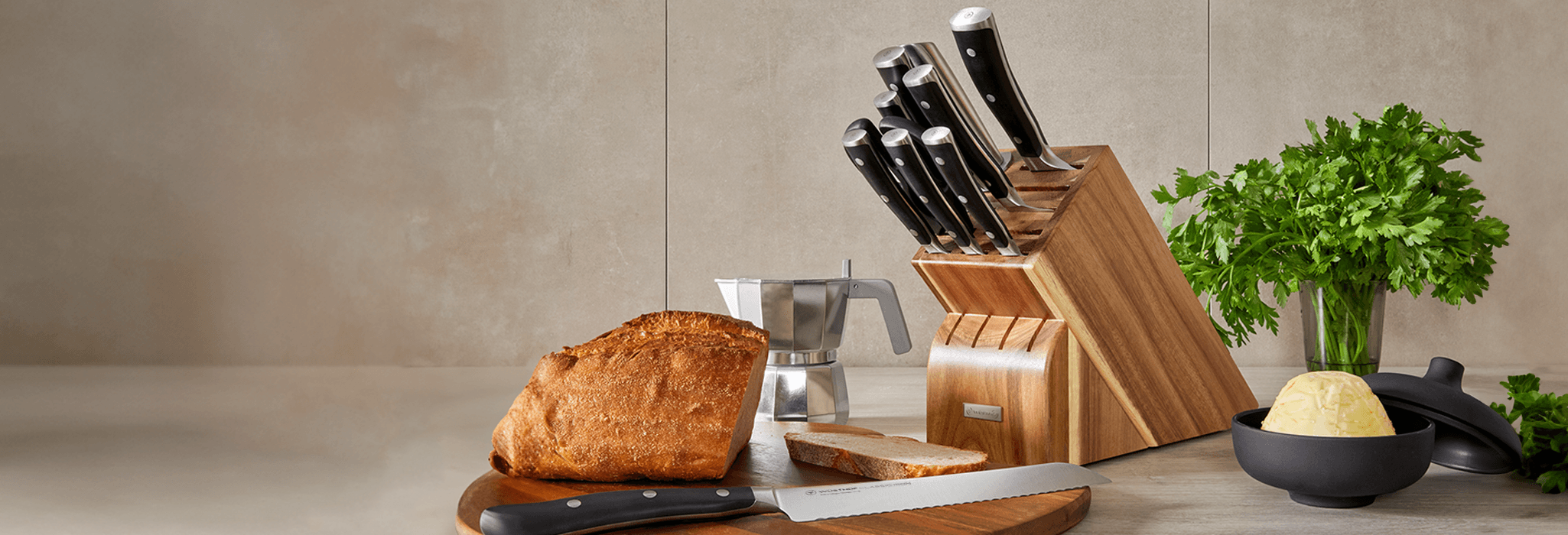 Knife set in block next to bread knife and loaf of bread