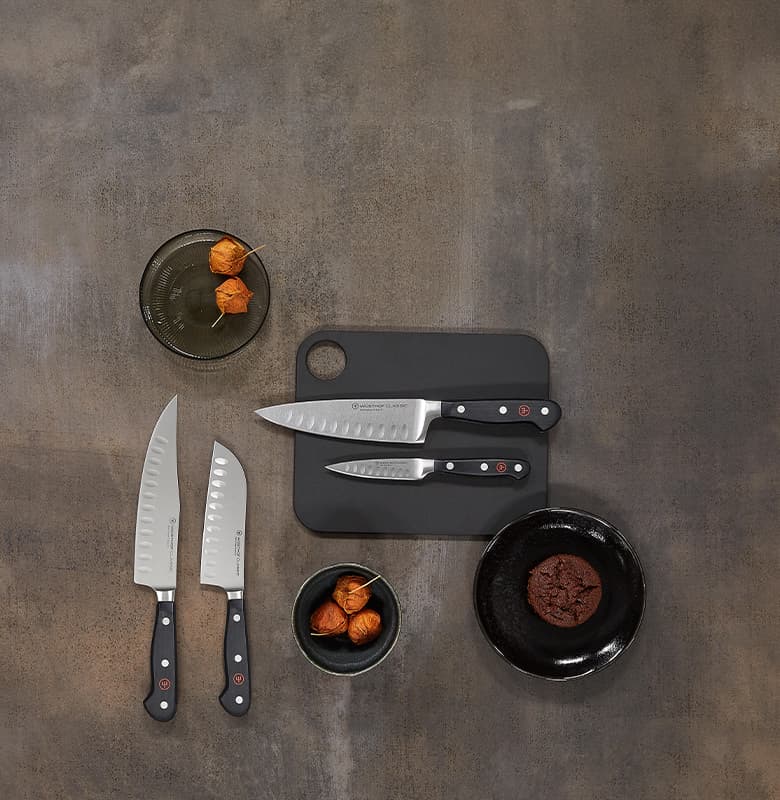 classic knives on a cutting board next to a cookie and dried flowers