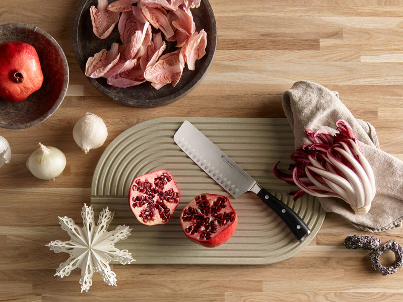 Classic Ikon knife on cutting board next to open pomegranate
