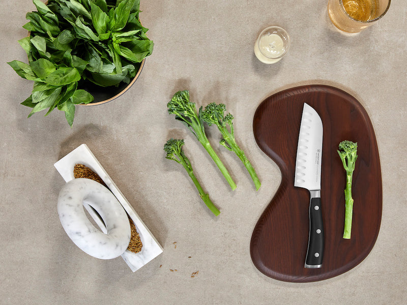 kitchen counter with vegetables and cutting board with knife