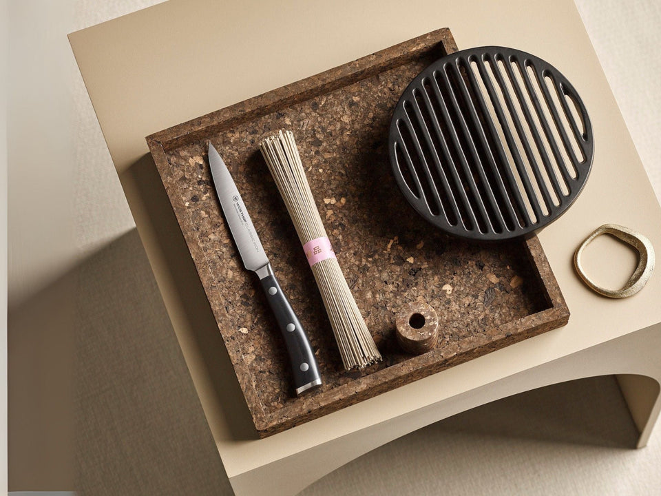 Tray with knife, noodles, and small grill on a beige surface