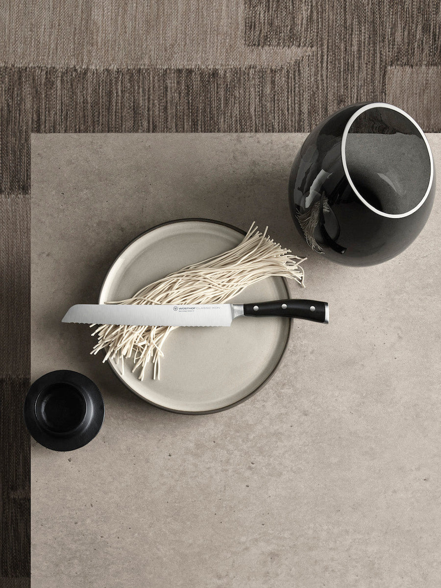 Napkin on a plate with a knife and black cup on a textured surface