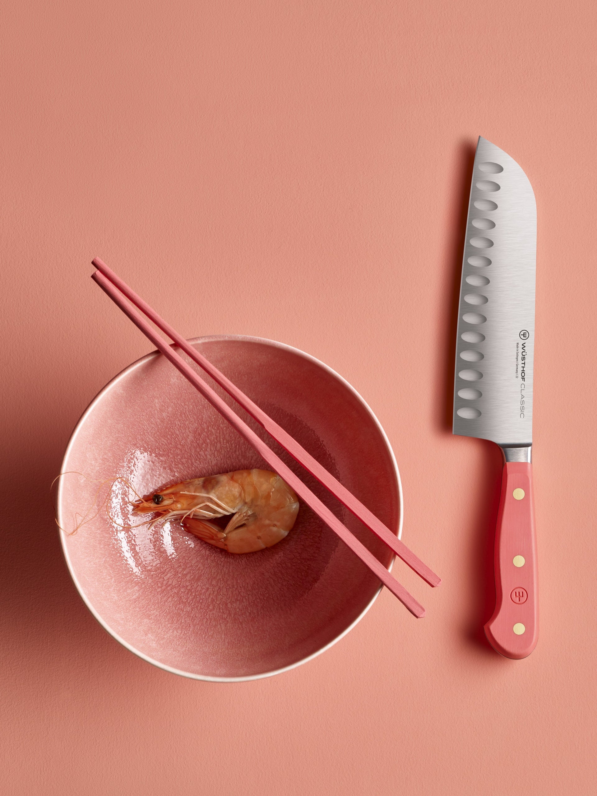 Coral peach hollow edge santoku near bowl with small fruit and chopsticks