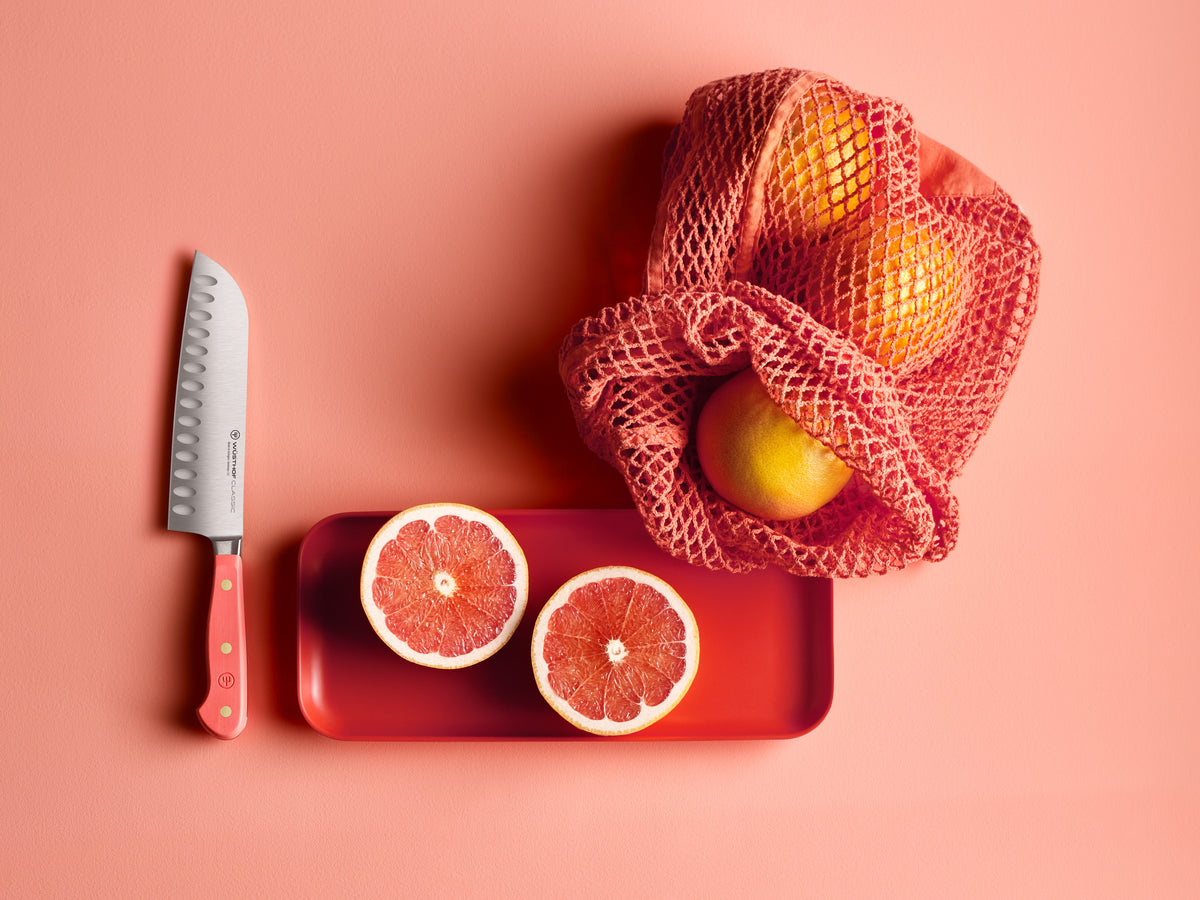Coral peach hollow edge santoku near vibrant fruit and netted bag