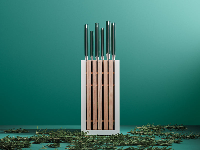 Set of knives in a wooden block on a teal background