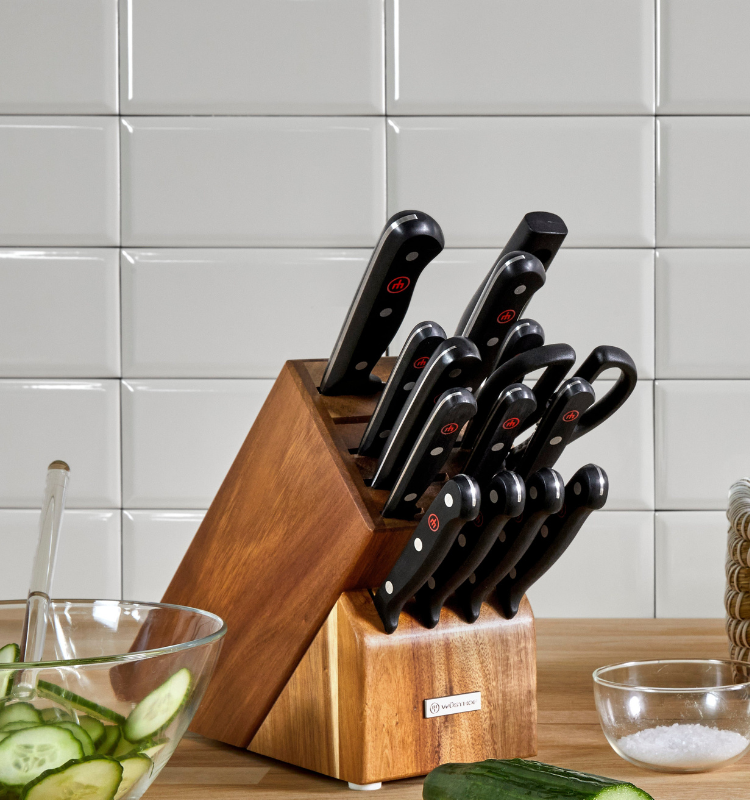 Kitchen counter with a knife block, bowls of vegetables, and a cutting board.