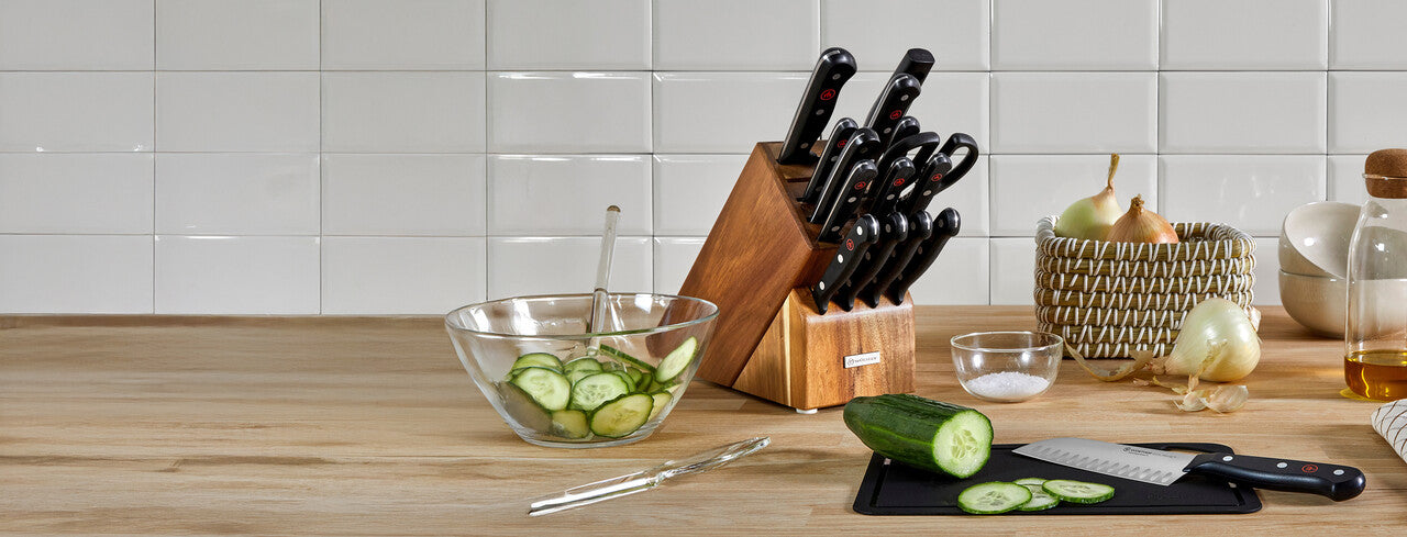 Kitchen counter with a knife block, bowls of vegetables, and a cutting board.