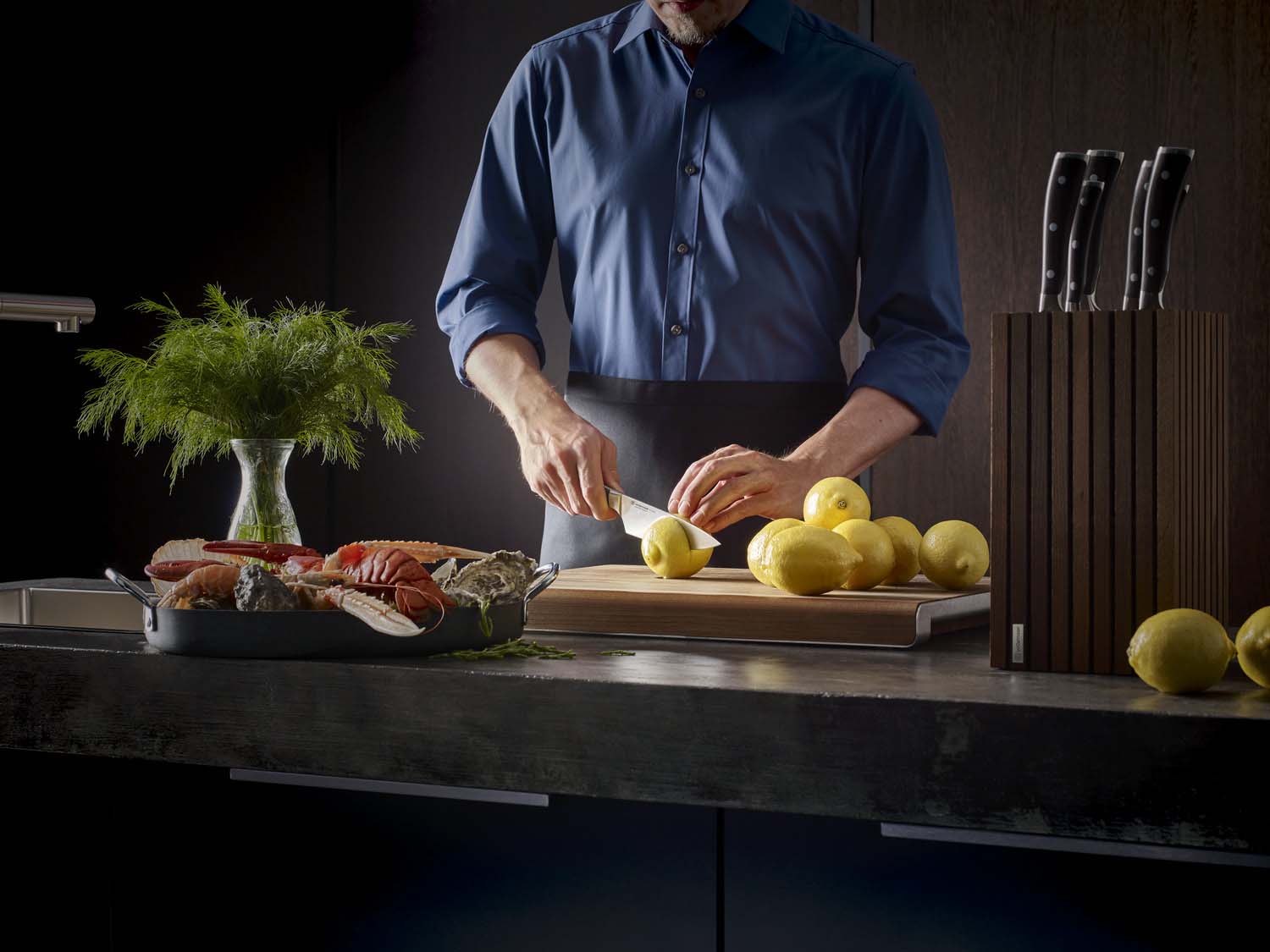Person preparing food with lemons on a cutting board in a kitchen setting.