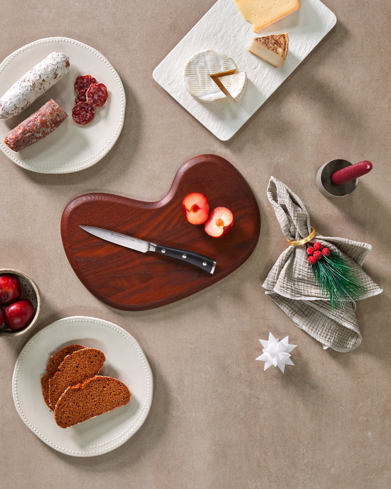 Dessert platter with bread, cheese, and fruit on a beige surface