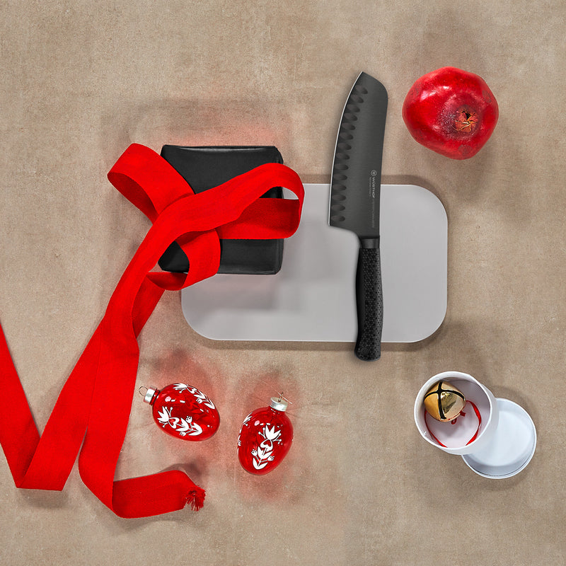 Knife, cutting board, red ribbon, and decorative items on a beige surface