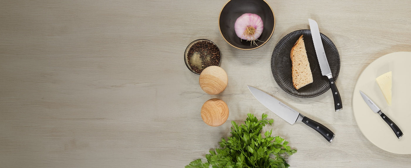 Table setting with bowls, bread, and knives on a wooden surface